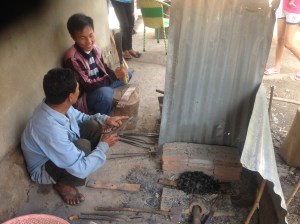 Mr. Pahn and Ahn (my guide) looking at a Laotian knife and the raw metal we just wedged of the car spring. 